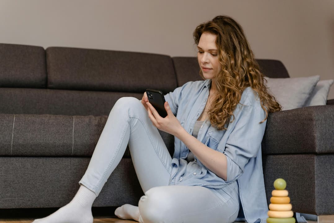 Mulher relaxada mexendo no celular, ilustrando procrastinação e tempo perdido que atrapalha o treino de corrida